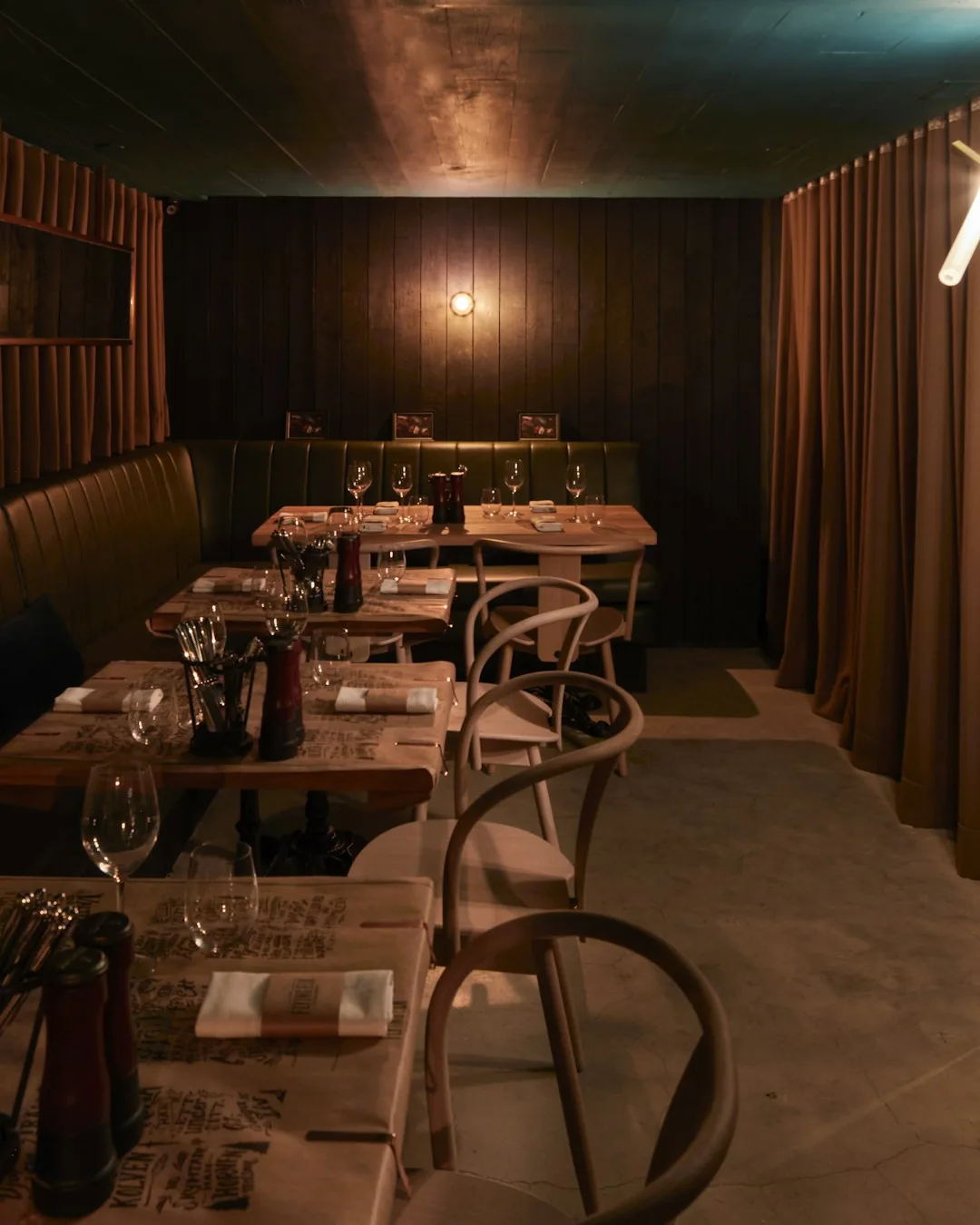 A chef drizzling sauce onto a delicately plated fine-dining dish in bright natural light.